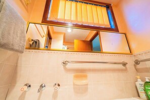 Un baño con espejo, perchero, jabonera y secamanos.