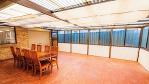 A conference room with a long table and chairs, large windows, and a brick wall. - Spacious Three-bedroom Holiday Home With the Entire House Exclusively Yours (Sanctuary Point)