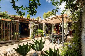 Eine Terrassenanlage mit Tisch und Stühlen, umgeben von Kübelpflanzen und einer Pergola.