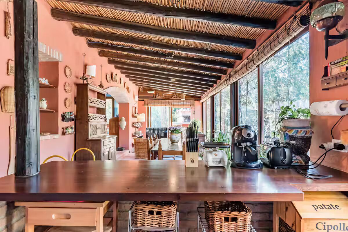 A kitchen with a wooden table, kitchen appliances, and a window with a view.
