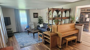 Una sala de estar con un piano, un sofá, una mesa de centro y un televisor.