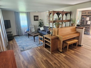 Un salon comprenant un piano, un canapé, une table basse et un téléviseur.