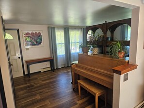 Une pièce avec un piano, un banc en bois et des plantes en pot.