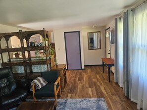 A living room with a wooden coffee table, a sofa, a wooden side table, a potted plant, and a door.