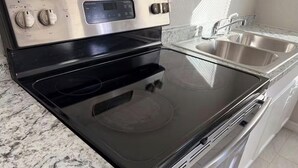 A kitchen with a black stovetop, stainless steel oven, and double sink. - Cozy 1-bedroom house in fantastic Cocoa with air conditioning (Cocoa)