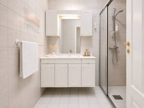A modern bathroom with a glass shower enclosure, white cabinetry, and a vanity with a mirror. - A40 - 2BR City Center - Cozy Apartment (Bergen)