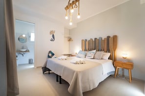 A bedroom with a bed, bedside table, and a nightstand with a lamp.