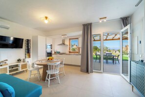 A modern kitchen with a dining area, a TV, and a view of the outdoors.
