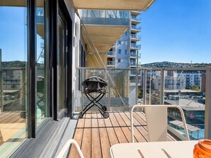 Un balcón con mesa y sillas, una parrilla y vistas de la ciudad.