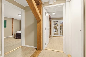 Un corridoio con travi in legno, un letto e una porta vetrata che dà sull'esterno.