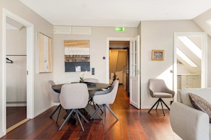 A dining area with a round table and four chairs, a sofa, and a chair with a tripod base. - Bryggen View - 4BR - Penthouse TG15-4 (Bergen)