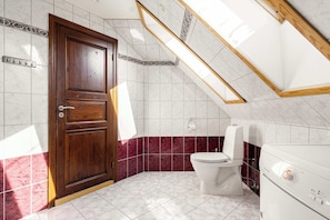 A bathroom with a wooden door, a white toilet, and a washing machine. - Bryggen View - 4BR - Penthouse TG15-4 (Bergen)