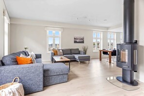 En moderne stue med sofa, skammel og pejs.