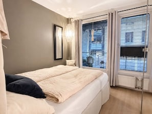 Un dormitorio con cama, candelabro y vistas por la ventana.
