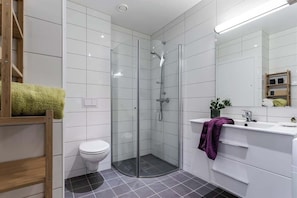 Une salle de bain moderne avec une douche à parois de verre, des toilettes blanches et un meuble-lavabo avec un miroir.