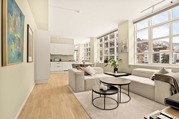 Een moderne woonkamer met een bank, salontafel en uitzicht op de stad door grote ramen.