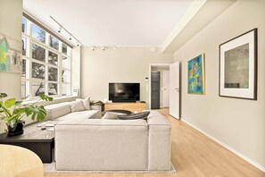 Een moderne woonkamer met een hoekbank, een flatscreen televisie en kunst aan de muren.