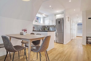 Una cocina moderna con comedor, suelo de madera y vistas al exterior.