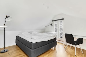 Un dormitorio con una cama, un escritorio, una silla y una lámpara de pie.