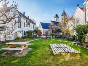 En innergård med två picknickbord, en kyrka med ett torn och bostadshus.