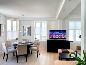 Ett modernt vardagsrum med en matplats, en platt-TV och en öppen spis.