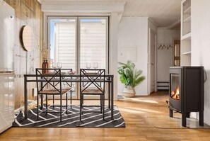 Una cocina moderna con comedor, estufa de leña y un amplio ventanal.