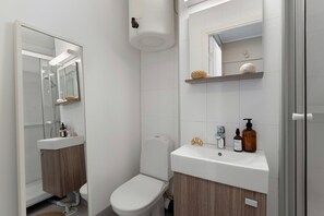 Et moderne badeværelse med toilet, håndvask og bruser.