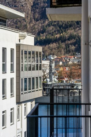 En moderne bygning med store vinduer, udsigt over en by med røde tage og et vandområde.