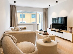 Una sala de estar moderna con un sofá, un reposapiés y un televisor de pantalla plana.