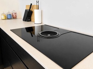 Una cocina moderna con una vitrocerámica negra elegante, un extractor empotrado y un diseño minimalista.