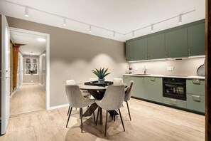 Uma cozinha moderna com armários verdes, uma mesa de jantar com cadeiras e uma planta em vaso.