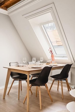 Un comedor con una mesa dispuesta para cuatro, sillas negras y una ventana con vistas.
