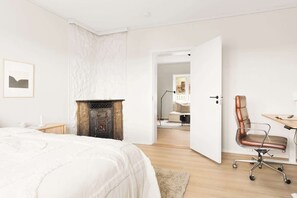 A bedroom with a bed, a fireplace, a desk with a chair, and a door leading to another room. - MK38 2BR Cozy Apartment Bergen (Bergen)