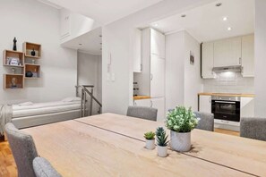 En kompakt opholdsstue med spiseplads, tekøkken og en lille soveplads.