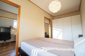 Una camera da letto con un letto, una scrivania, una sedia, un armadio e una lampada a soffitto.