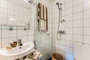 Un bagno con cabina doccia in vetro, lavabo con specchio e portasciugamani.