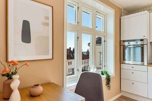 Una cucina con un'ampia finestra, mobili bianchi e un'area pranzo con tavolo e sedie.