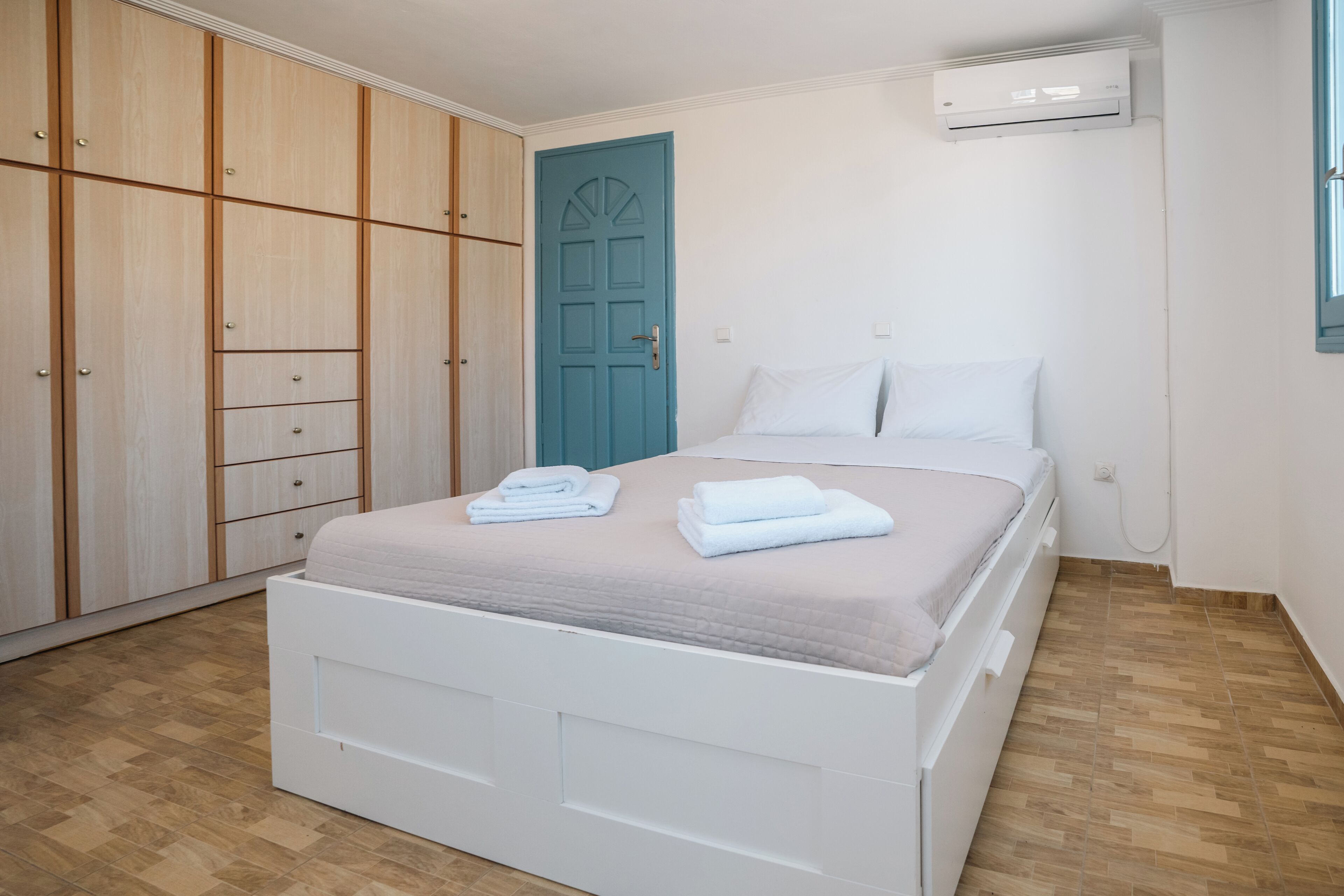 Ein Schlafzimmer mit einem Bett, einem Kleiderschrank, einer Tür und einer Klimaanlage.