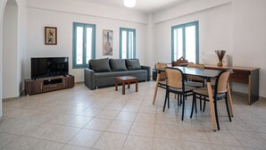 Un soggiorno con divano, televisore, tavolo da pranzo, sedie e opere d'arte alle pareti.