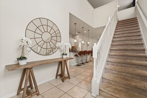 A staircase with a beige carpet, a wooden bench with potted plants, and a large wall clock. - EV_1800 - 6BR / 5BA Luxury Villa w/ Private Pool & Spa, Game Room, Resort Access (Kissimee)
