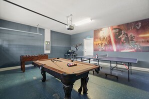 A pool table, foosball table, ping pong table, and Star Wars themed wall art in a room with blue brick walls and a door. - EV_1800 - 6BR / 5BA Luxury Villa w/ Private Pool & Spa, Game Room, Resort Access (Kissimee)