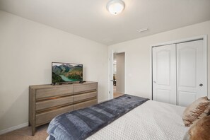 Ein Schlafzimmer mit einem Bett, einem Schminktisch, einem Fernseher und einer Tür.