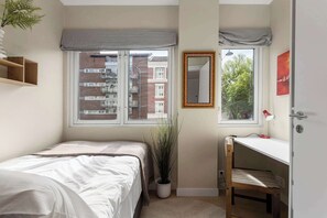 A bedroom with a bed, a desk, a mirror, a potted plant, and a window with a view of buildings. - 5BR 2Bath Frogner - Parking - Vigelandsparken (Oslo)
