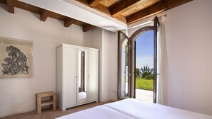 Een slaapkamer met een groot bed, een kledingkast, een klein krukje en een schilderij aan de wand.