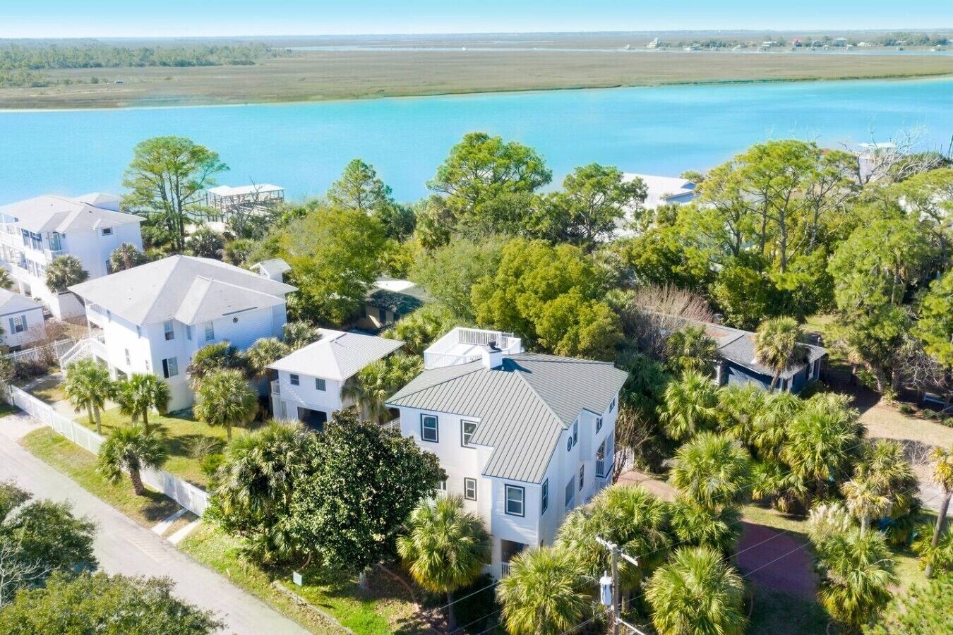 A residential area with houses surrounded by trees and a large body of water in the background.