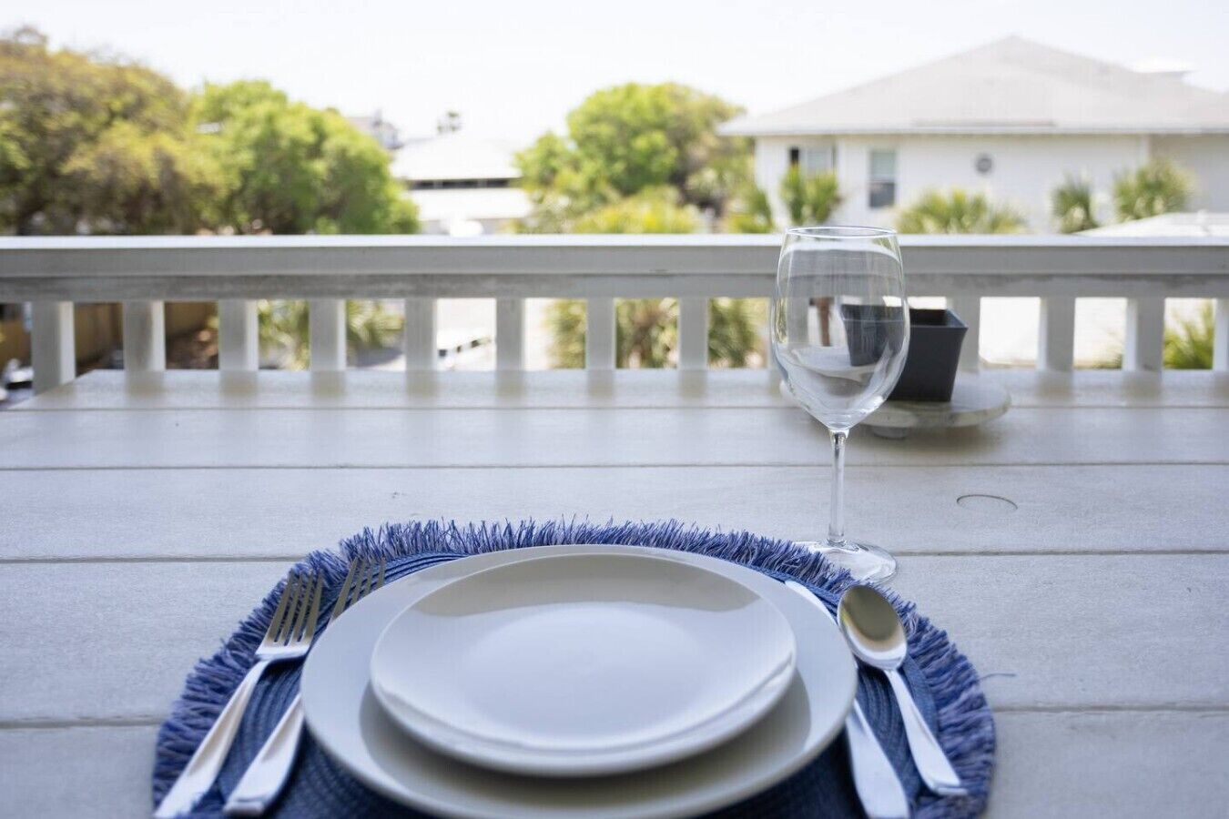 A dining table with a white tablecloth, a blue placemat, and a glass of water.