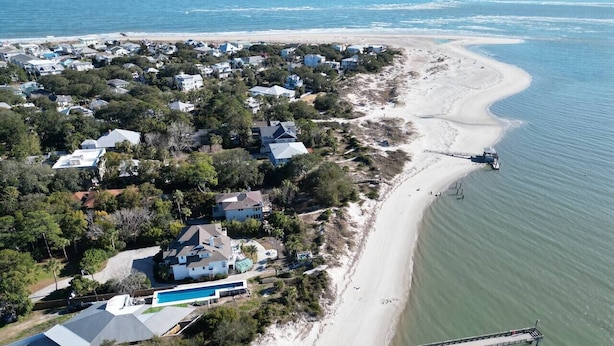 Ein Luftbild eines Küstenwohngebiets mit Häusern, einem Strand und einem Steg.