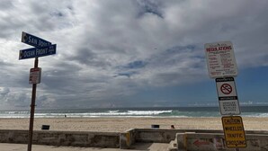 A beach with a signpost indicating directions and regulations, including a prohibition on motorized vehicles.