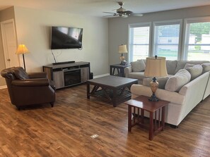 A living room with a flat-screen TV, a sofa, a coffee table, and a fireplace. - Peaceful 3 bedroom handicapped accessible house with AC in charming Hamilton. (Hamilton)