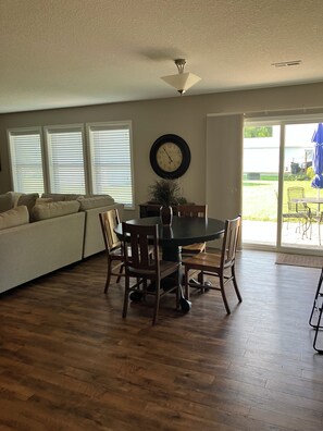 A dining area with a round table, chairs, and a clock on the wall.